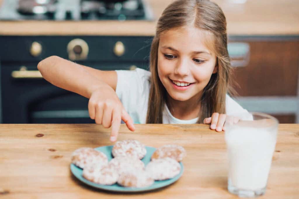 Bambina seduta a tavola che sta per mangiare dei biscotti